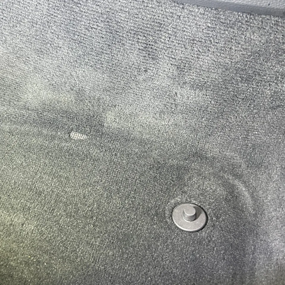 Beschädigte Stelle im Fahrzeugteppich vor der Bearbeitung